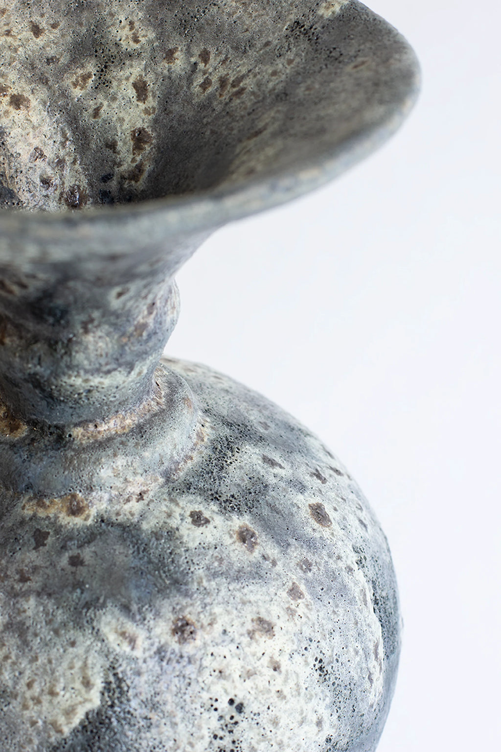 Canoa Lab Ánfora Gecko Vase, a handcrafted ceramic vase featuring a unique dark grey, light grey, and cream volcanic glaze with a highly textured, porous finish and speckled brown accents. This artisanal stoneware piece showcases a classic ánfora silhouette with a flared rim and rounded body, embodying an organic modern aesthetic. Perfect for wabi-sabi or rustic minimalist shelf styling in contemporary living rooms or bedrooms.