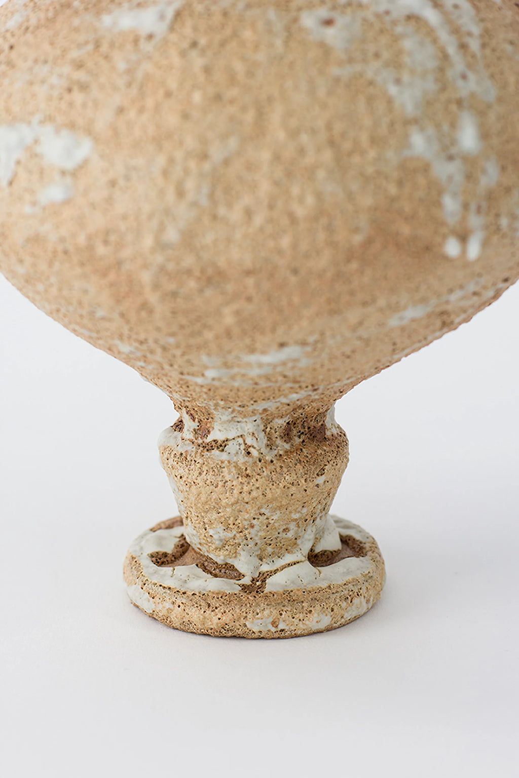 Canoa Lab Arq 002 Vase, a handcrafted stoneware vase in warm beige and sand tones, featuring a highly textured, porous volcanic finish with natural cream glaze drippings and an organic sculptural pedestal base. This rustic ceramic vase is perfect for wabi-sabi or organic modern shelf styling, adding an artisanal touch to japandi living rooms or minimalist entryways.