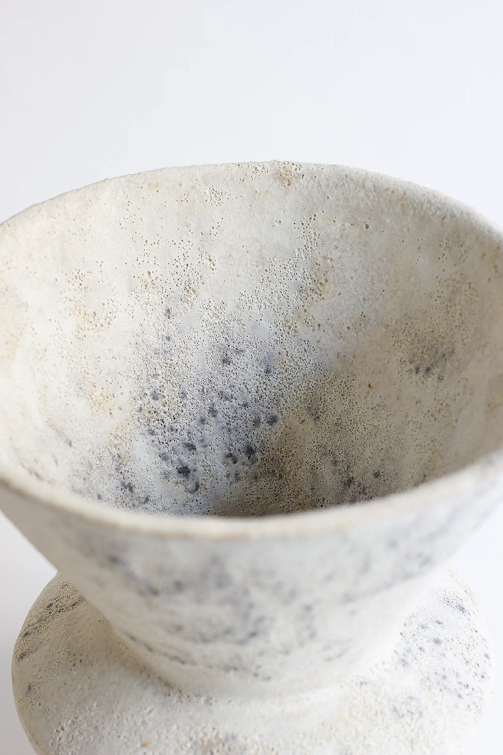 Canoa Lab Arq 010 Cárabo Vase, an elegant ceramic piece with a textured, off-white and speckled gray interior, featuring a wide, gently sloped opening, displayed on a pristine white background.