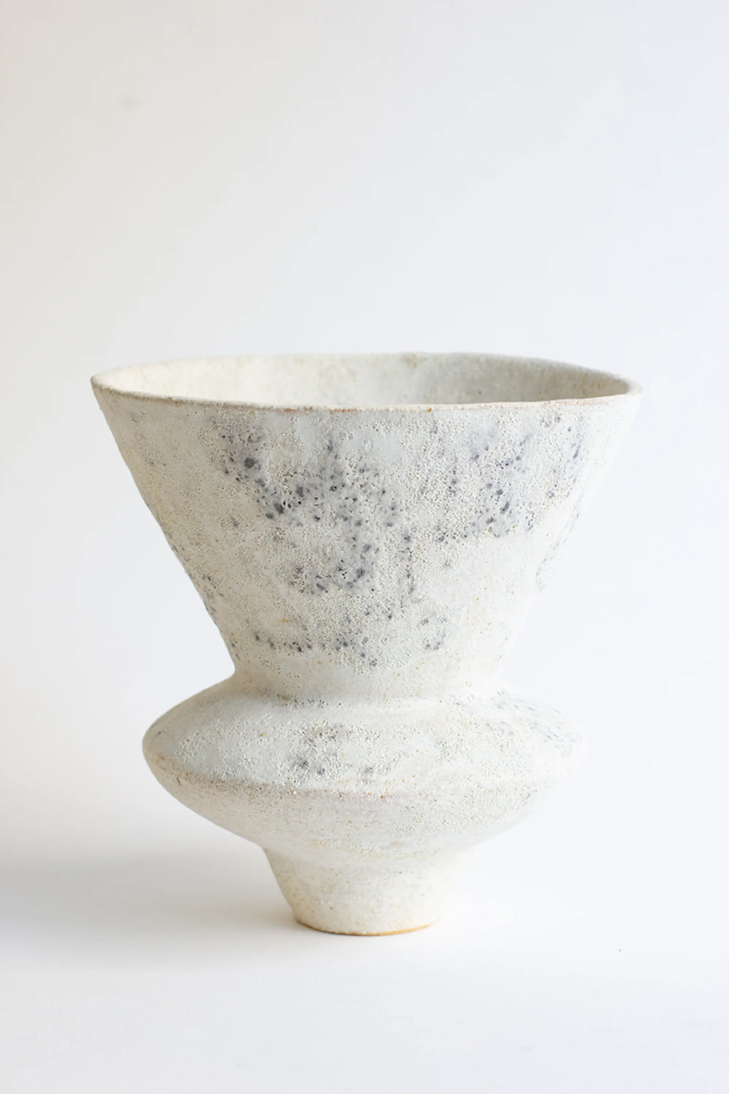 Canoa Lab Arq 010 Cárabo Vase, a modern, textured ceramic vase in off-white with subtle dark speckles, featuring a wide flared top and a rounded, bulbous base, displayed on a white background.