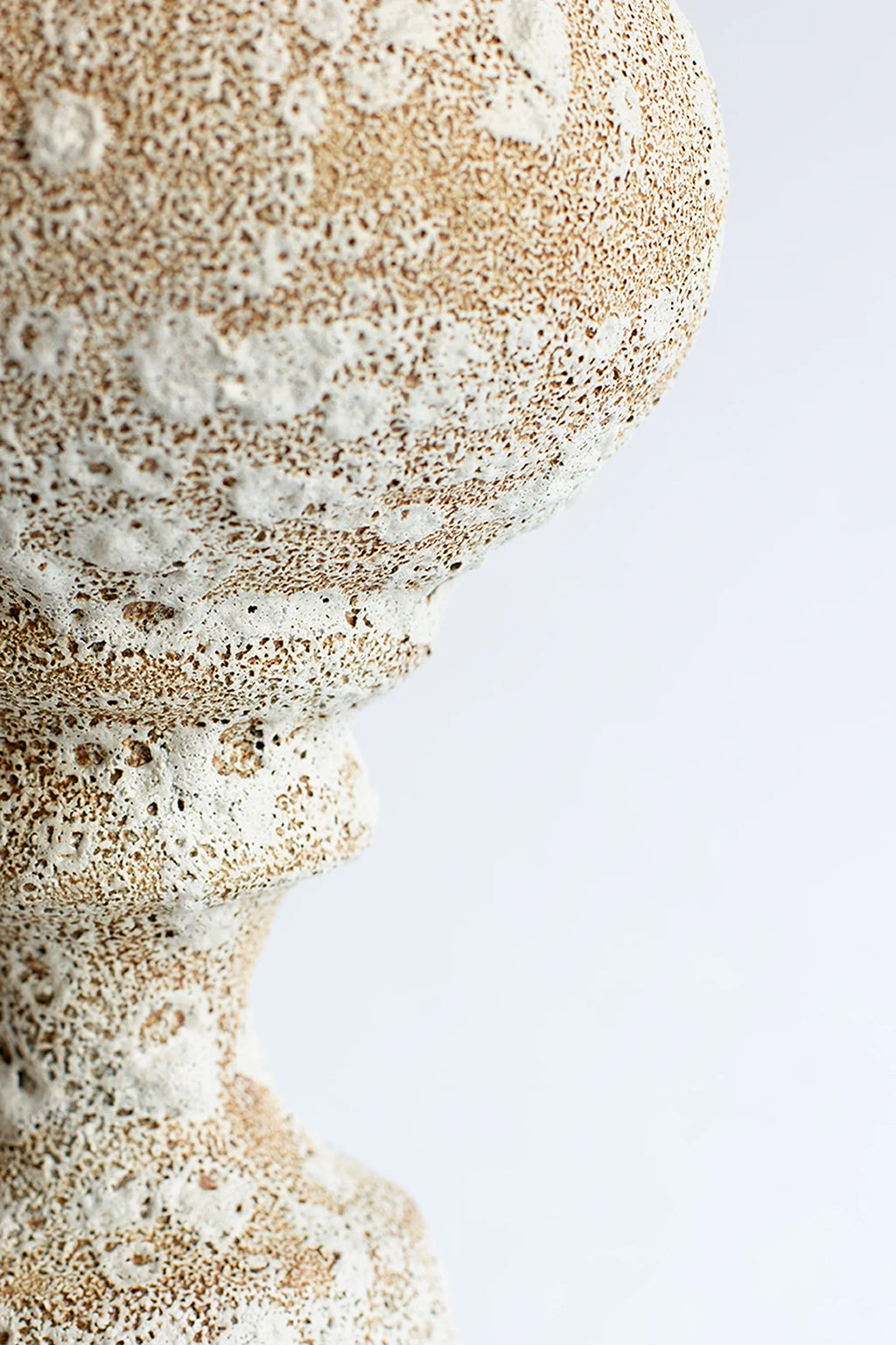 Canoa Lab Arq 012 Vase, a close-up side view revealing the intricate, porous texture of the light beige ceramic with prominent white glaze accents, creating a rustic, artisanal finish on a white background.