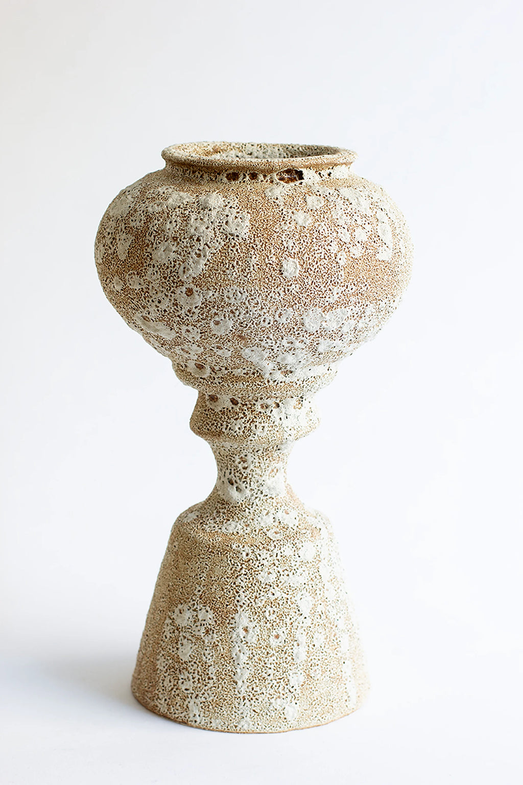 Canoa Lab Arq 012 Vase, a handcrafted stoneware vase with a unique porous volcanic texture in natural cream and sandy beige tones, featuring a sculptural bulbous body atop an architectural pedestal base. This organic modern ceramic vase is perfect for wabi-sabi shelf styling or as a contemporary focal point in minimalist living rooms and entryways.
