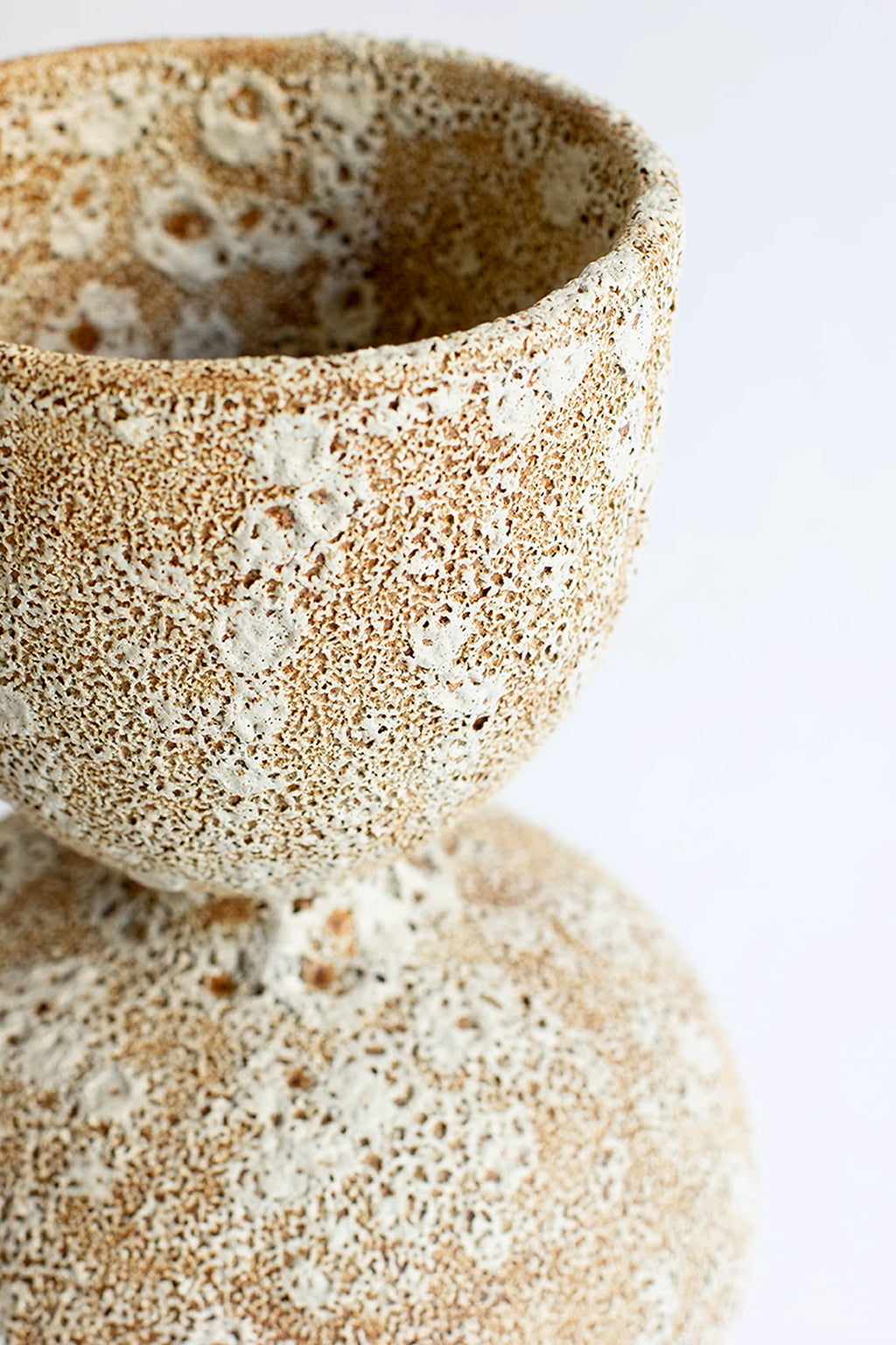 Canoa Lab Arq 013 Vase, a detailed close-up of the textured ceramic surface, showcasing the intricate pattern of raised white speckles against a warm, sandy beige base. The artisanal finish gives this modern vase a unique, organic feel. Displayed on a white background.