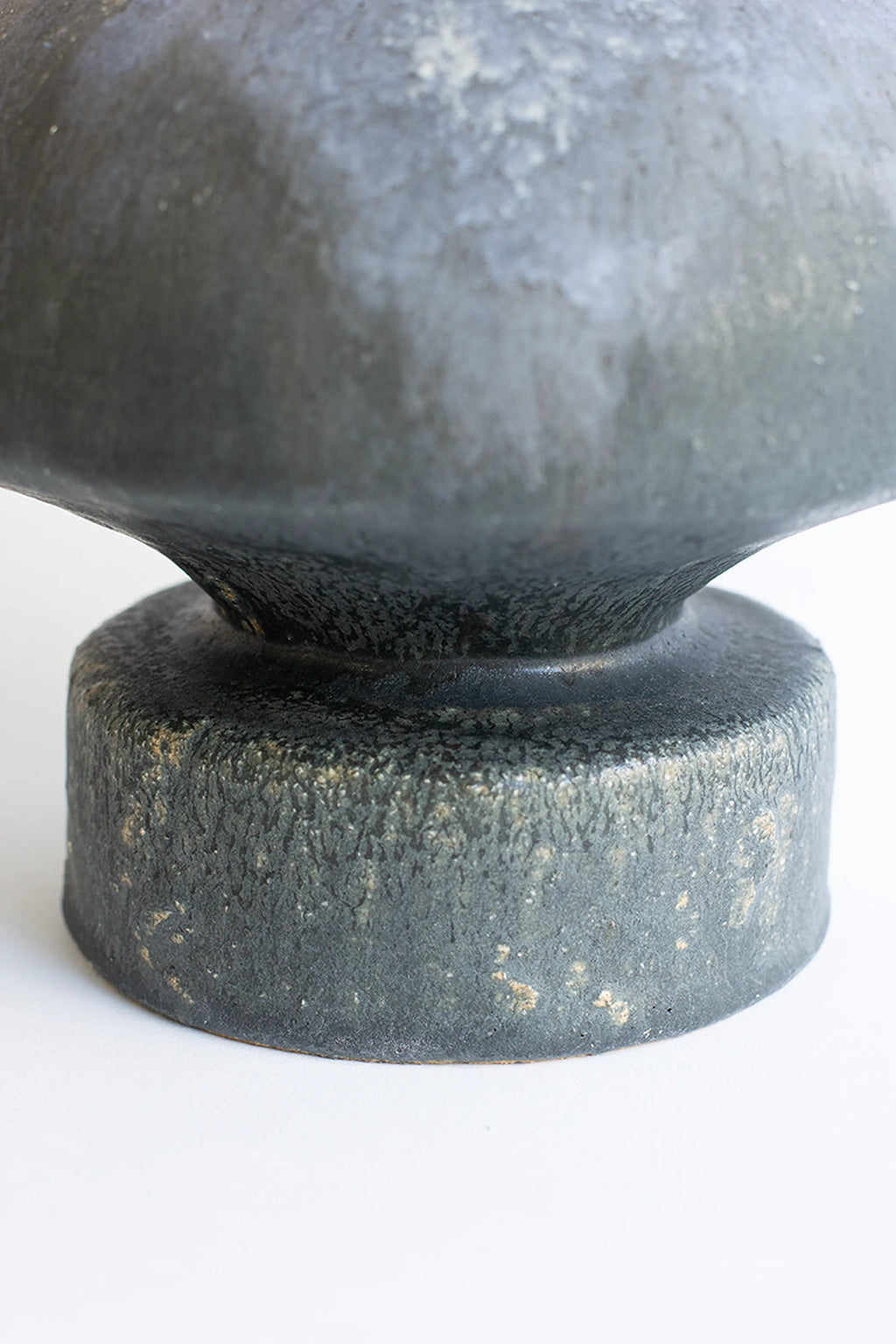 Canoa Lab Arq 014 Vase, a dark grey handcrafted ceramic vase with a highly textured, porous volcanic finish and a sculptural organic shape.