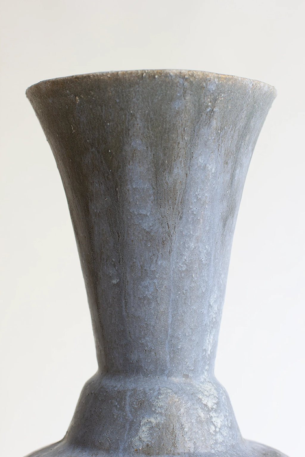 Canoa Lab Arq 014 Vase, a handcrafted grey ceramic vase featuring a unique porous, volcanic texture and a flared, organic silhouette. This artisanal stoneware piece showcases a matte, desaturated slate grey finish with subtle lighter mottling and darker streaks, ideal for wabi-sabi or organic modern shelf styling. Perfect as a minimalist accent for living rooms, bedrooms, or entryway consoles.