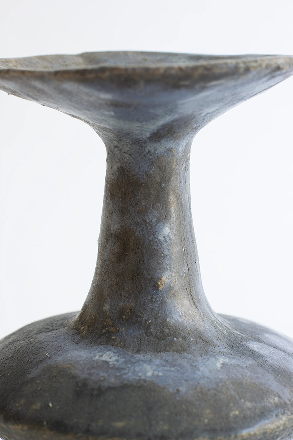 Canoa Lab Arq 015 Vase, a close-up of the vase's neck and flared top, showcasing the rough, textured charcoal gray ceramic material with subtle blue undertones and artisanal imperfections, on a white background.