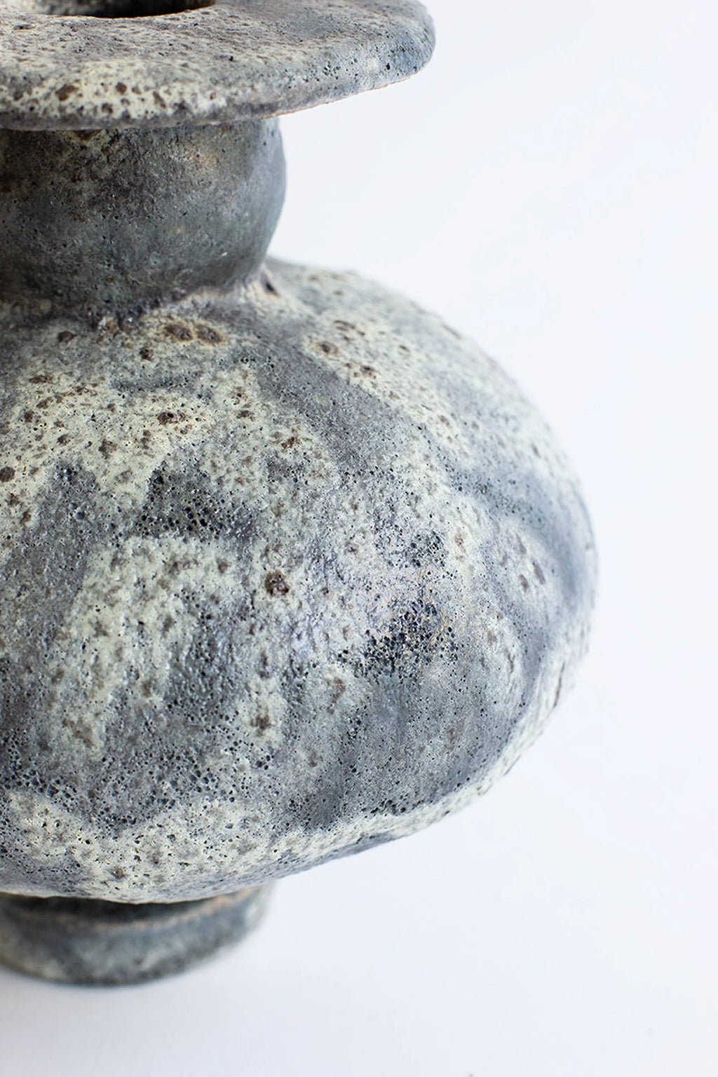 Canoa Lab Cálpide Gecko Vase, a detailed side view showcasing the vase's unique bulbous shape and the intricate, textured gray and white glaze. The artisanal ceramic finish adds depth and character, presented on a white background.