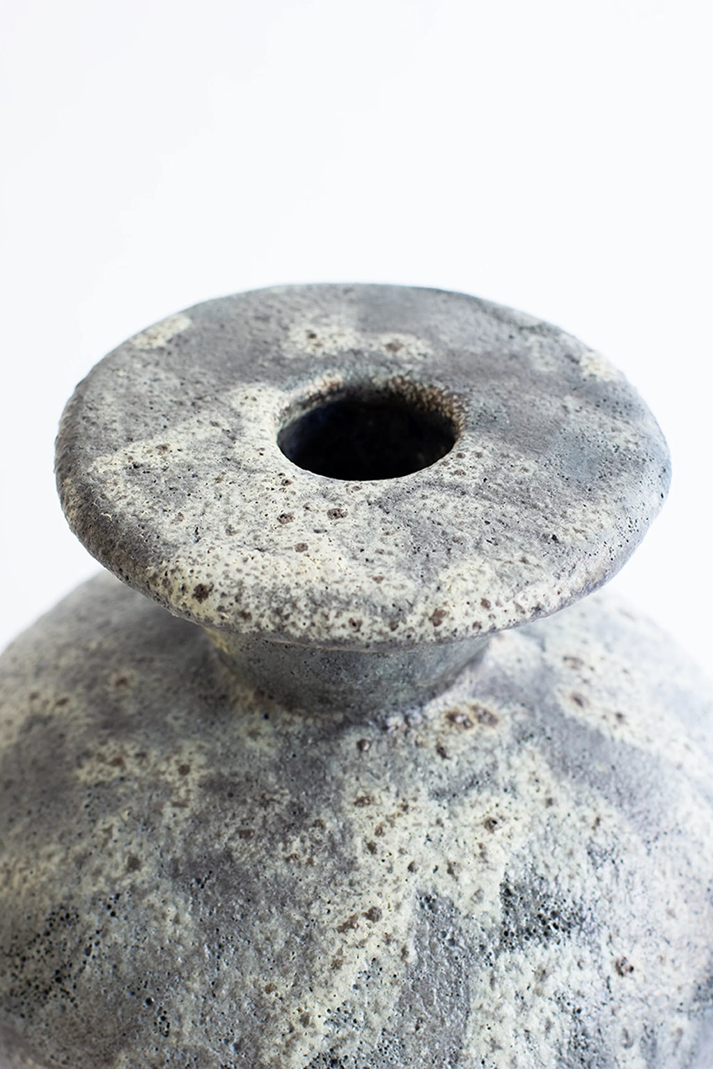 Canoa Lab Cálpide Gecko Vase, a close-up view of the vase's textured rim and opening. The mottled gray and white glaze with a rough, organic finish is clearly visible, highlighting its artisanal quality on a white background.