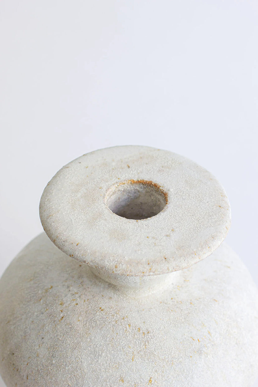 Canoa Lab Cálpide Blanco Hueso Vase, a close-up of the top opening, showcasing its rustic, textured off-white ceramic material with subtle speckles, displayed on a clean white background. The elegant, modern design features a wide, flat rim.