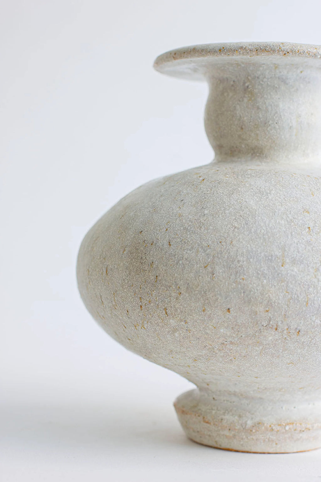 Canoa Lab Cálpide Blanco Hueso Vase, a close-up side view revealing its elegant, bulbous body and textured off-white ceramic finish. The rustic, handcrafted material with subtle speckles adds a modern, premium touch, displayed on a white background.