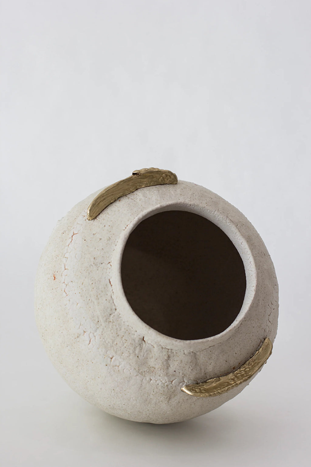 Canoa Lab Isolated n.10 Vase, a top-down view of the round, off-white ceramic vase, revealing its wide opening and the two golden, leaf-like accents on its textured, crackled surface, displayed on a white background.