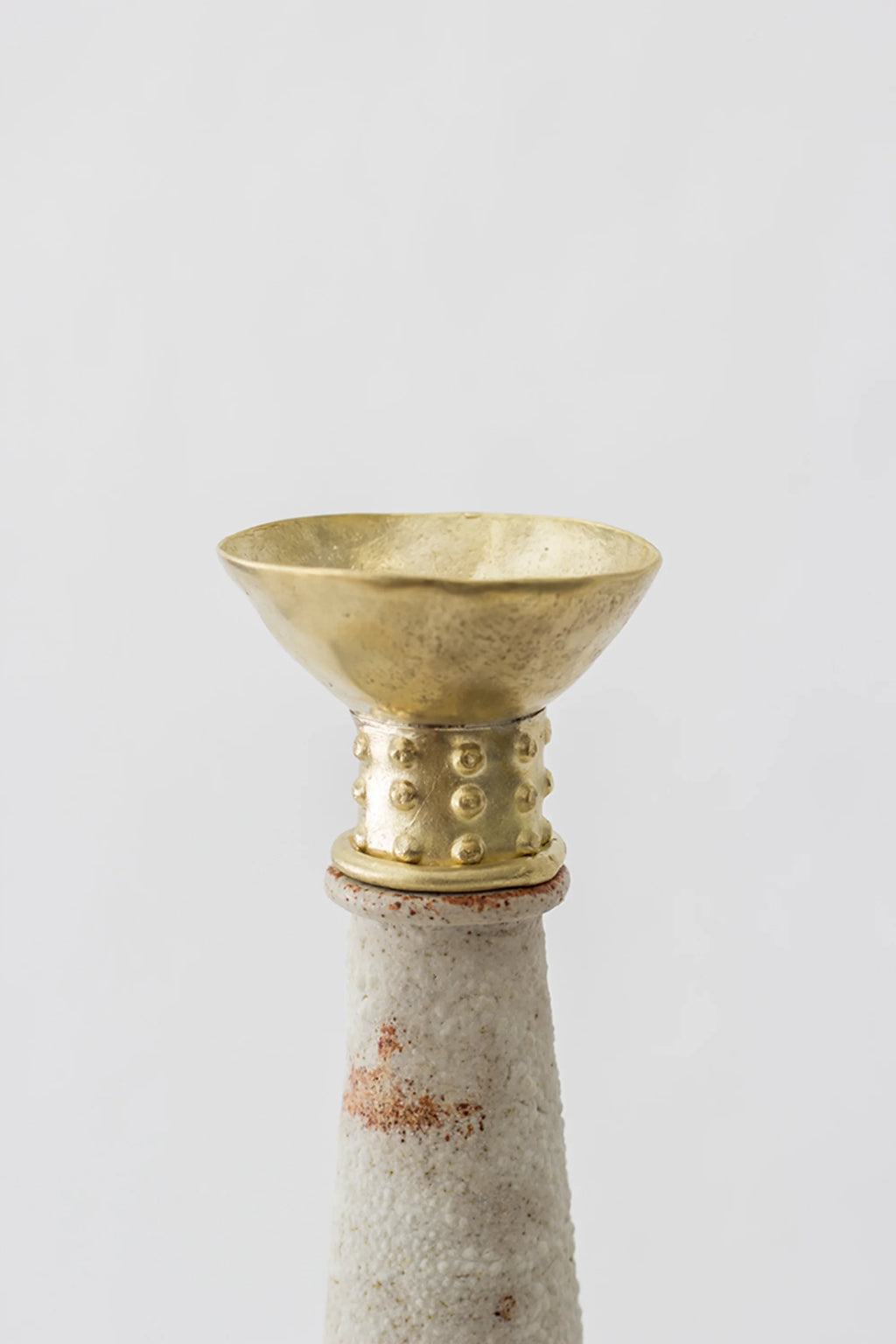 Canoa Lab Isolated n.13 Vase, a close-up of the elegant golden top of the vase, featuring a textured, dotted band around its base, contrasting beautifully with the slender, light beige ceramic neck, on a white background.