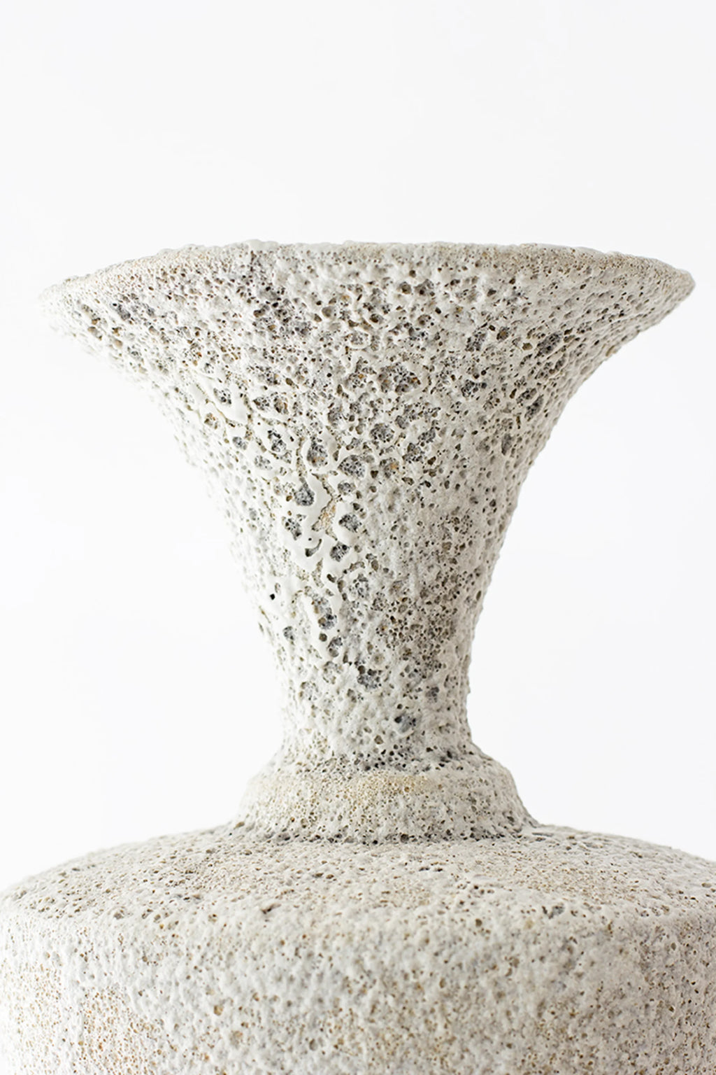 Canoa Lab Isolated n.20 Vase, a close-up of the elegant ceramic vase's flared top, showcasing its intricate, highly textured, porous off-white surface with subtle dark specks, on a white background.