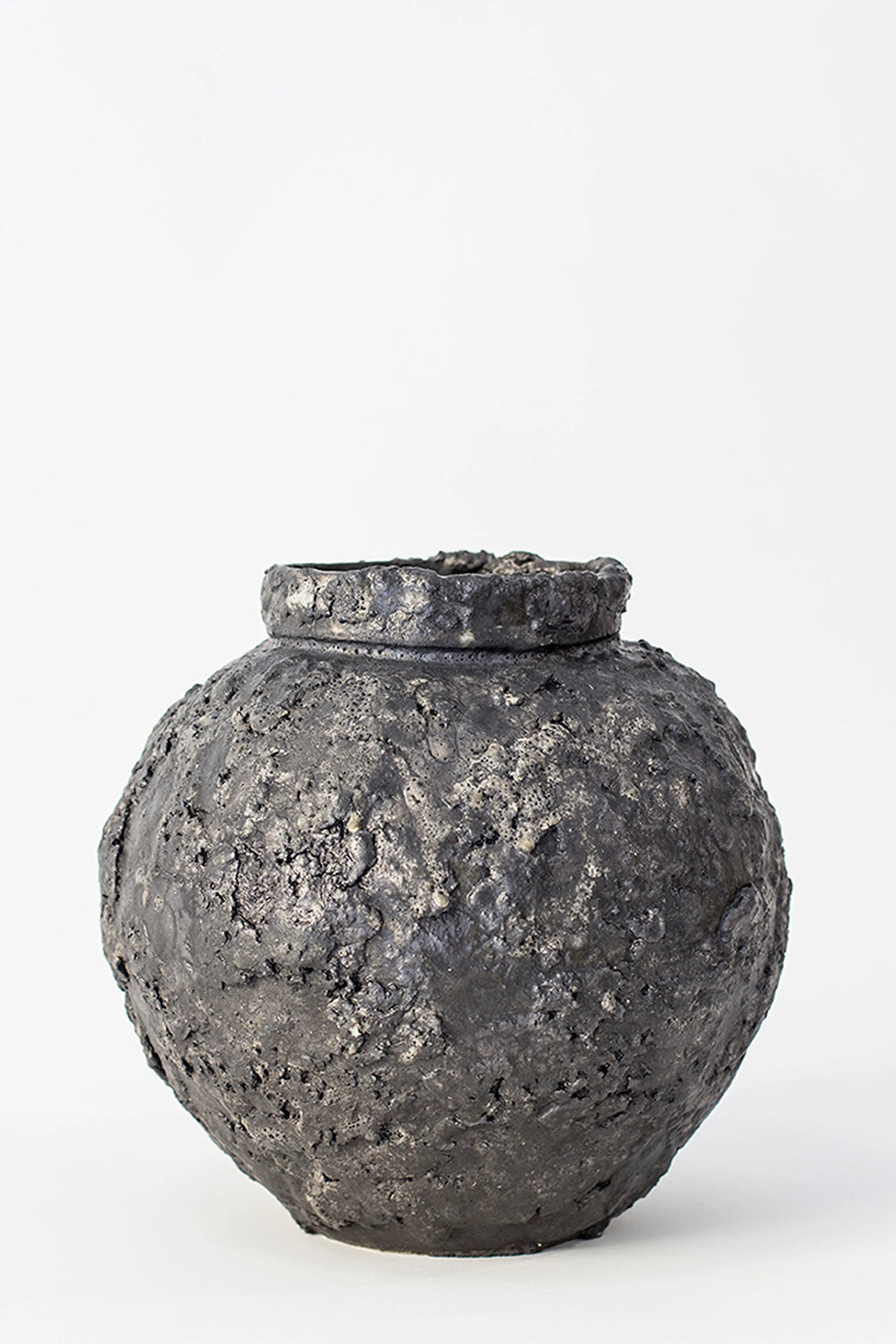 Canoa Lab Isolated n.22 Vase, a unique, dark gray, spherical ceramic vase with an organic, heavily textured, volcanic surface, displayed on a clean white background.