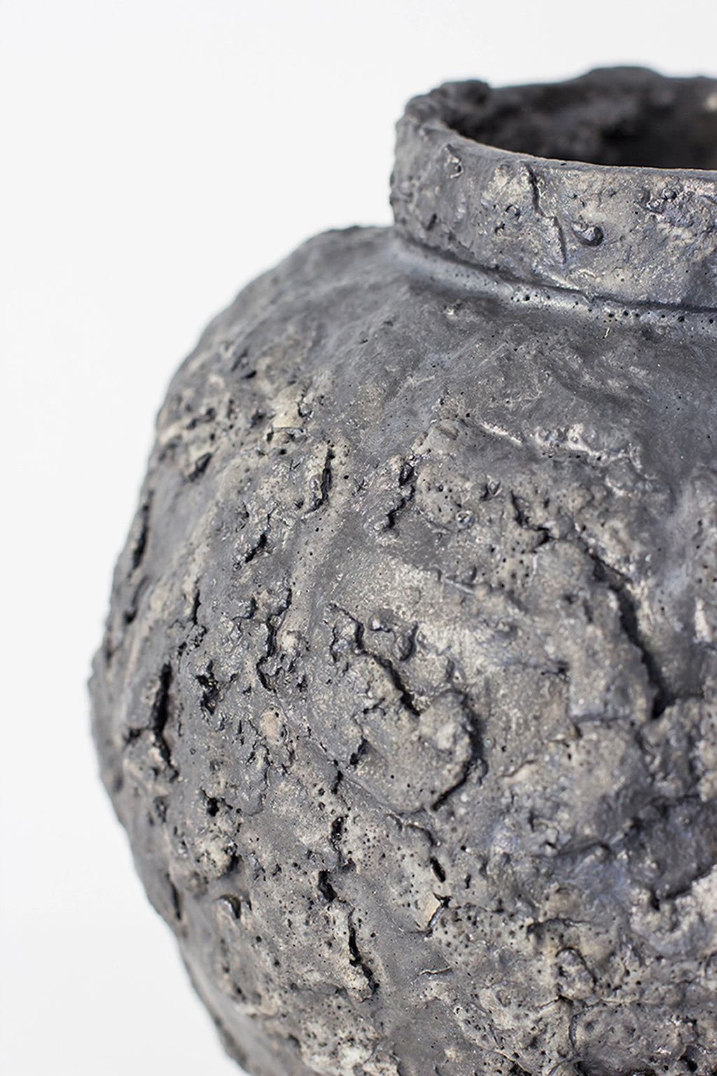 Canoa Lab Isolated n.22 Vase, a close-up of the dark gray, spherical ceramic vase, highlighting its intricate, rough, and highly textured surface resembling volcanic rock.