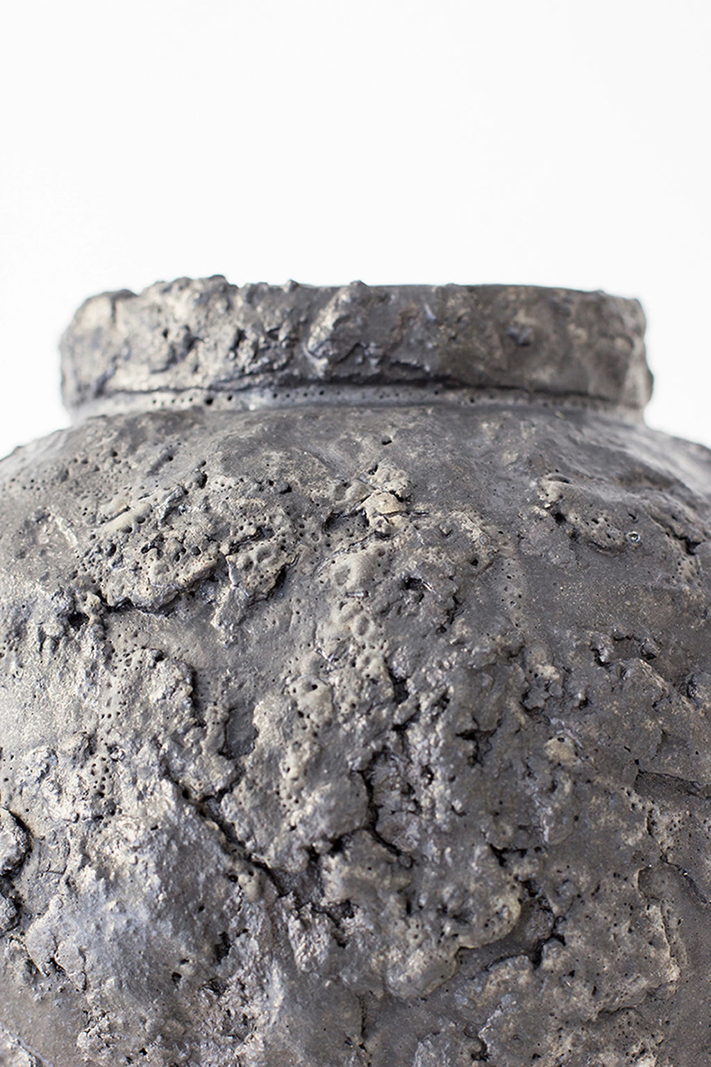 Canoa Lab Isolated n.22 Vase, a detailed close-up of the top rim and upper body of the dark gray, spherical ceramic vase, showcasing its rugged, organic texture.
