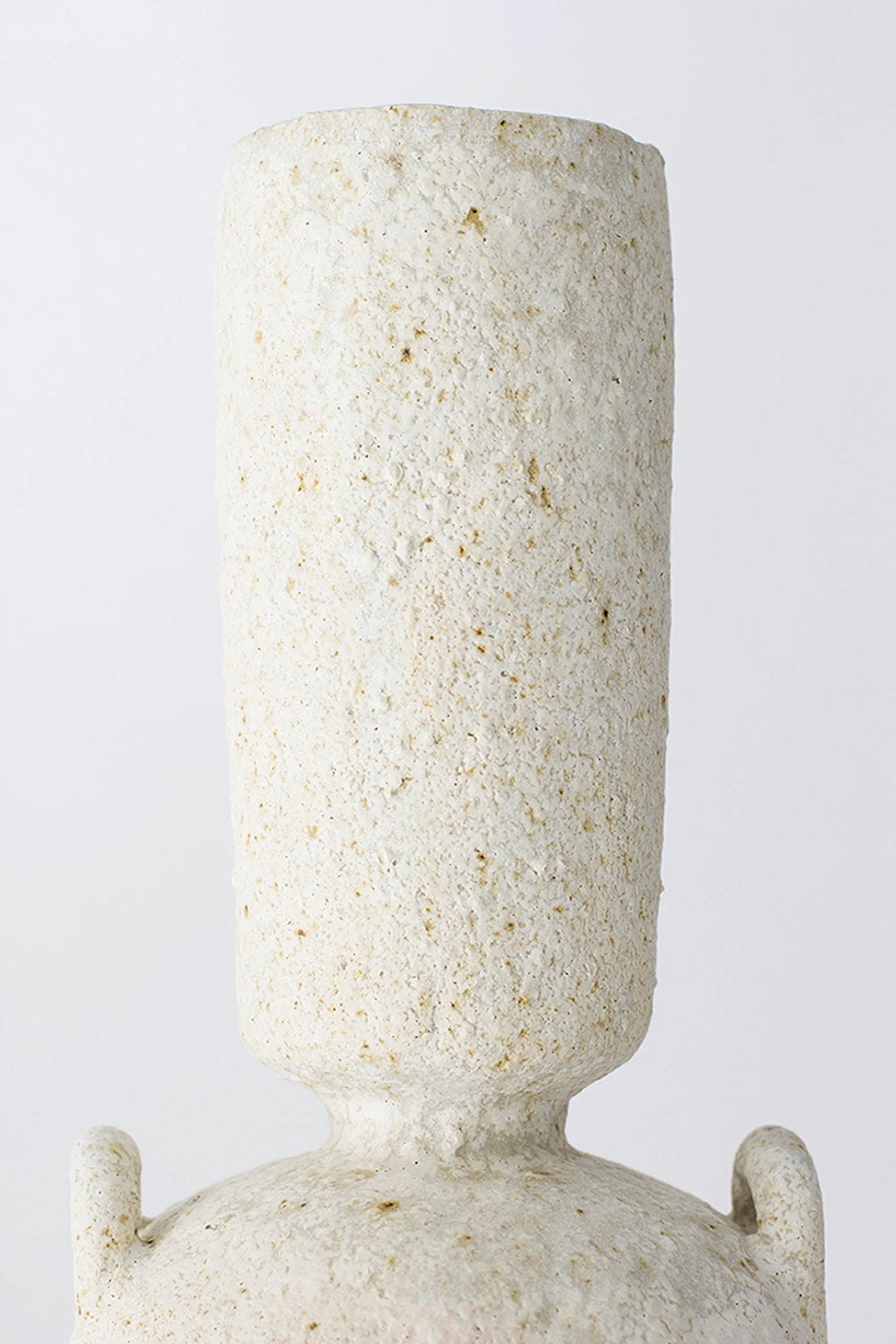 Canoa Lab Isolated n.23 Vase, a close-up of the vase's tall, cylindrical neck, showcasing its rough, porous, and textured off-white ceramic surface, emphasizing the artisanal quality and unique finish, on a white background.