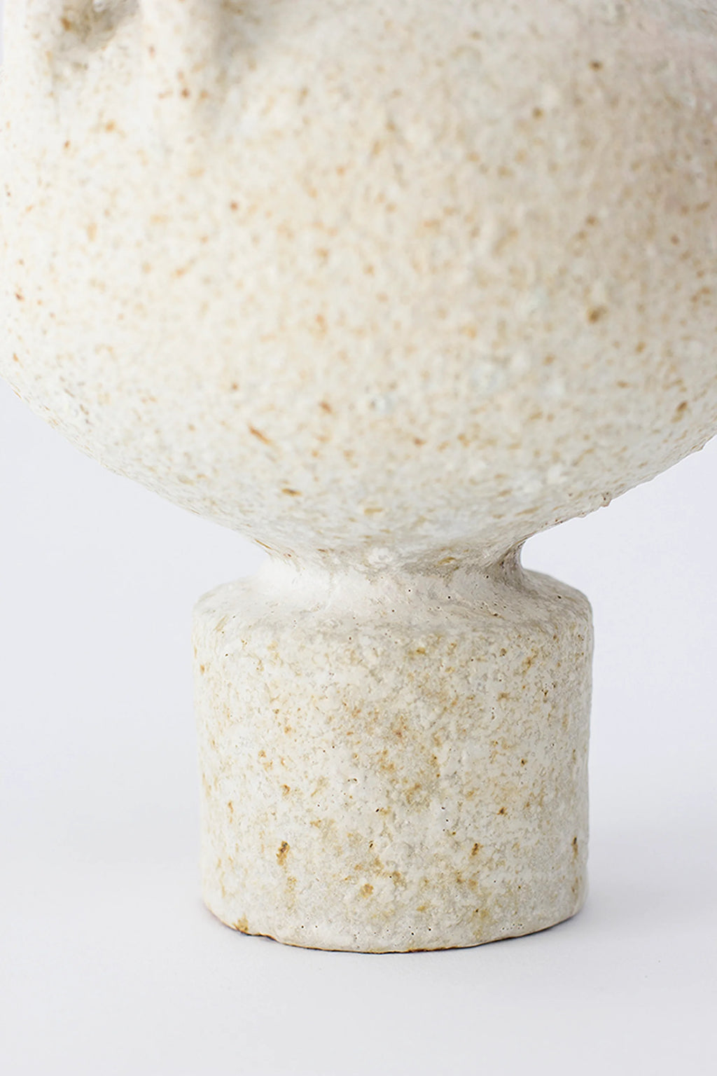 Canoa Lab Isolated n.23 Vase, a close-up of the vase's sturdy, cylindrical base and the lower part of its rounded body, highlighting the coarse, off-white ceramic texture and handcrafted details, on a white background.