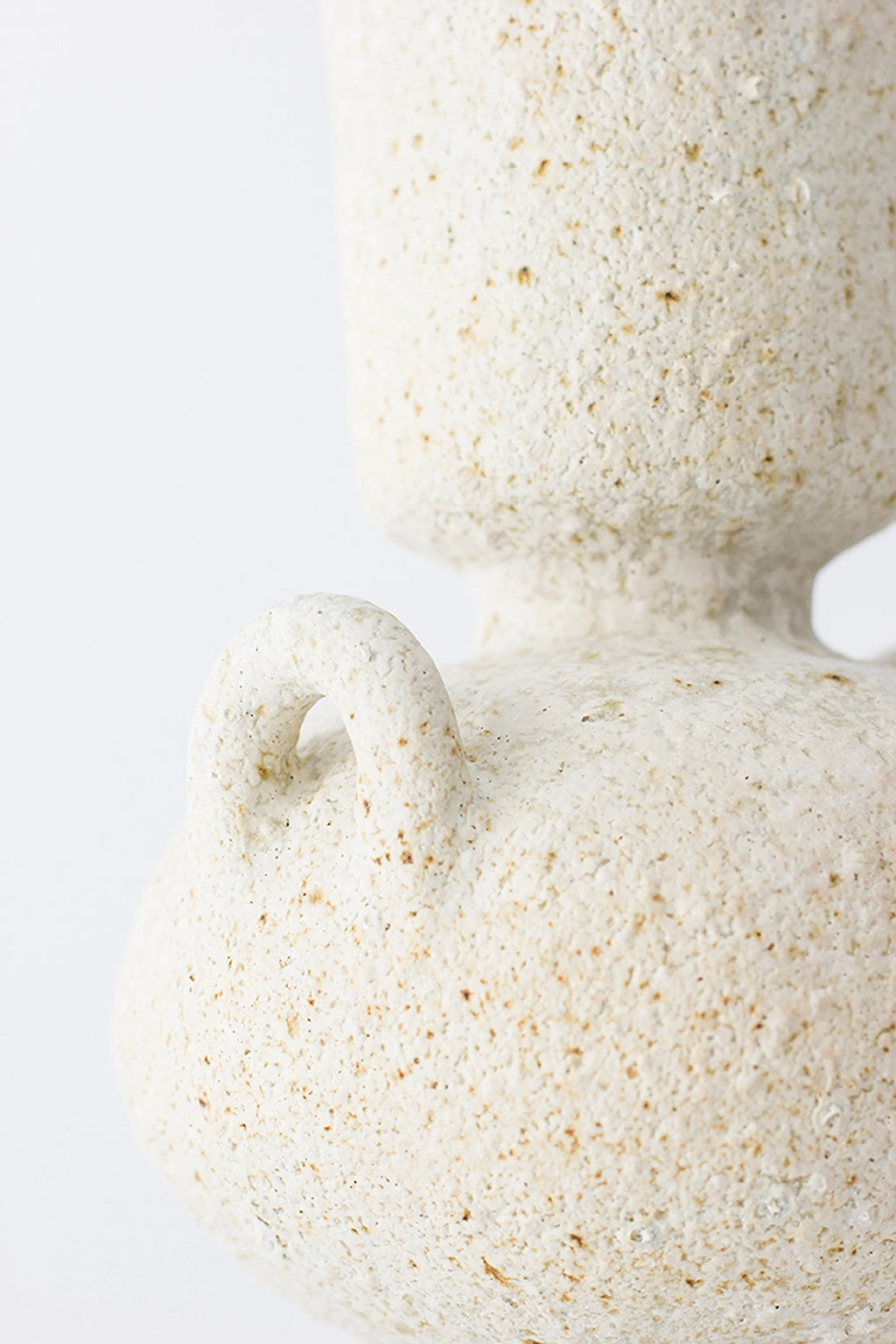 Canoa Lab Isolated n.23 Vase, a cream-colored handcrafted ceramic vase featuring a distinctive porous volcanic texture with earthy sand and brown flecks, shaped in a classic Mediterranean urn silhouette with a small loop handle.