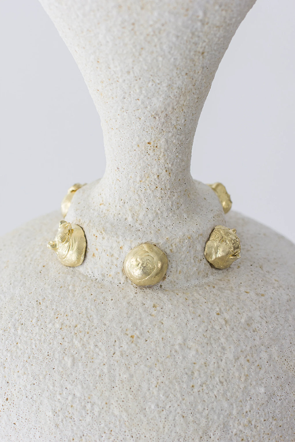Canoa Lab Isolated n.24 Vase, a close-up of the neck and shoulder, showcasing the textured off-white ceramic and the distinctive golden, organic-shaped embellishments, highlighting its luxurious detail.