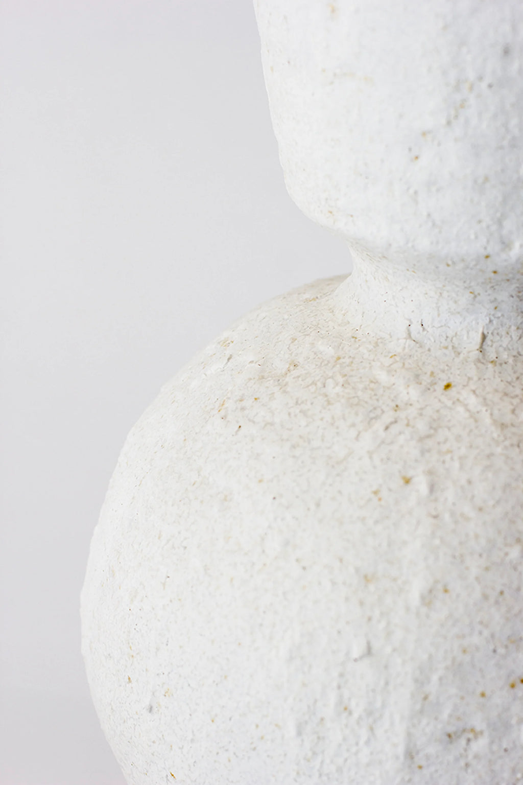Canoa Lab Isolated n.26 Vase, a side view close-up emphasizing the unique, organic curve of the vase's waist, showcasing its distinct rough, off-white ceramic texture with subtle imperfections, against a white background.