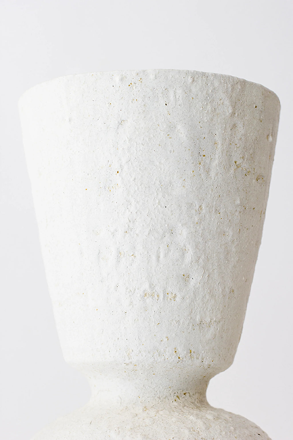 Canoa Lab Isolated n.26 Vase, a close-up of the upper, tapered section of the elegant off-white ceramic vase, revealing its rustic, textured surface with visible speckles and a subtle crackled effect, on a white background.