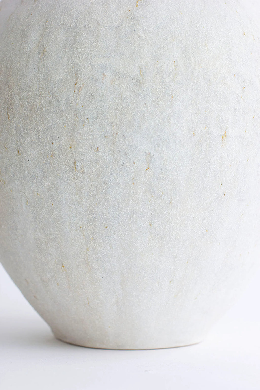 Canoa Lab Isolated n.31 Vase, a close-up of the lower body of the tall, white ceramic vase, showcasing its smooth, subtly textured, matte finish and elegant curvature.