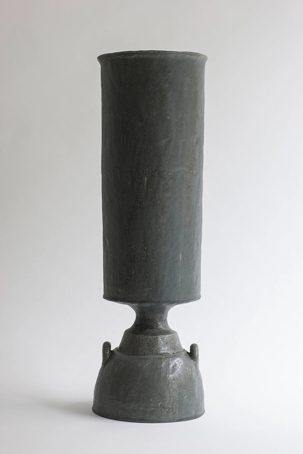 Canoa Lab Isolated n.32 Vase, a tall, commanding ceramic vase in a deep, matte charcoal gray, featuring a cylindrical top and a bell-shaped base with two small handles, displayed on a clean white background.