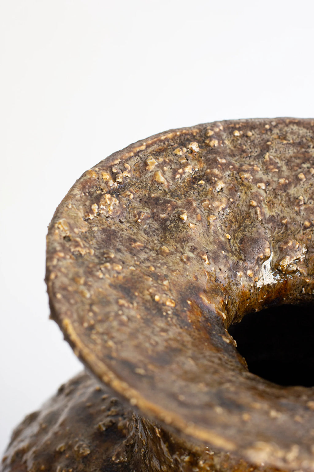 Canoa Lab Isolated n.34 Vase, a close-up of the top opening, highlighting the rough, textured surface and the rich, dark brown glaze with subtle variations, against a white background.
