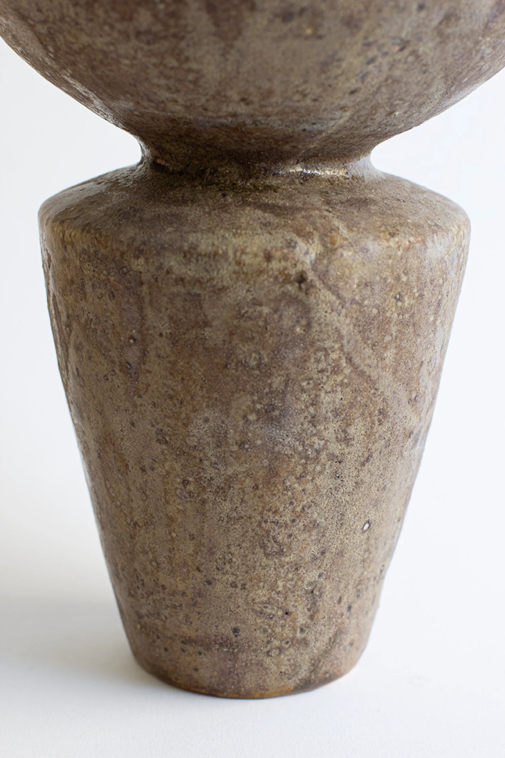 Canoa Lab Lebes Búfalo Vase, a detailed close-up of the textured, earthy brown and green glazed ceramic body, highlighting its rustic, organic surface and conical shape.