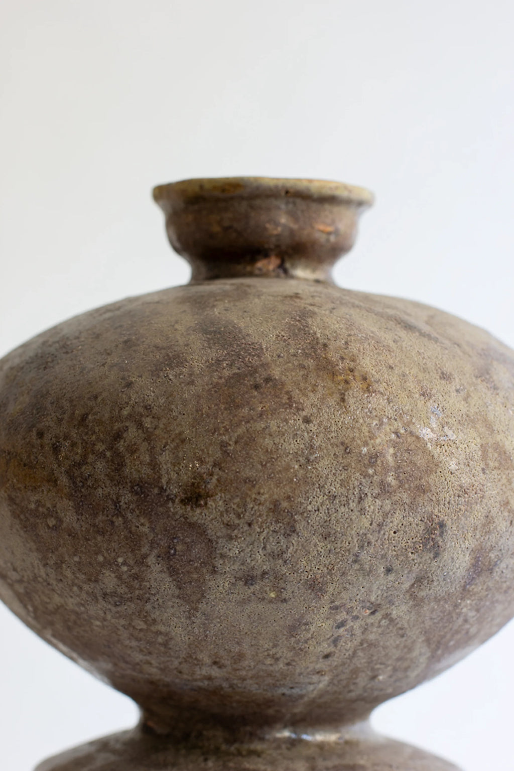 Canoa Lab Lebes Búfalo Vase, a close-up view of the upper body, revealing the rich, mottled earthy brown and green glazed ceramic with a textured, antique-like finish.