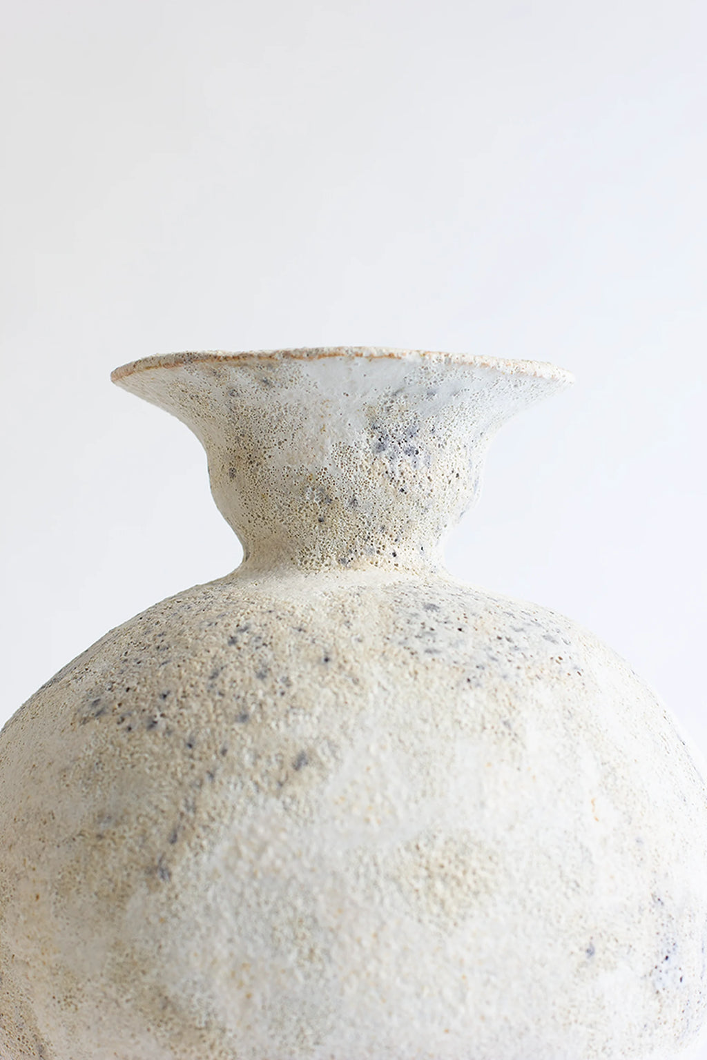 Canoa Lab Lekytho Cárabo Vase, a close-up of the upper portion of the artisanal ceramic vase, highlighting its narrow neck and wide, textured rim, with a speckled off-white finish, against a clean white background.