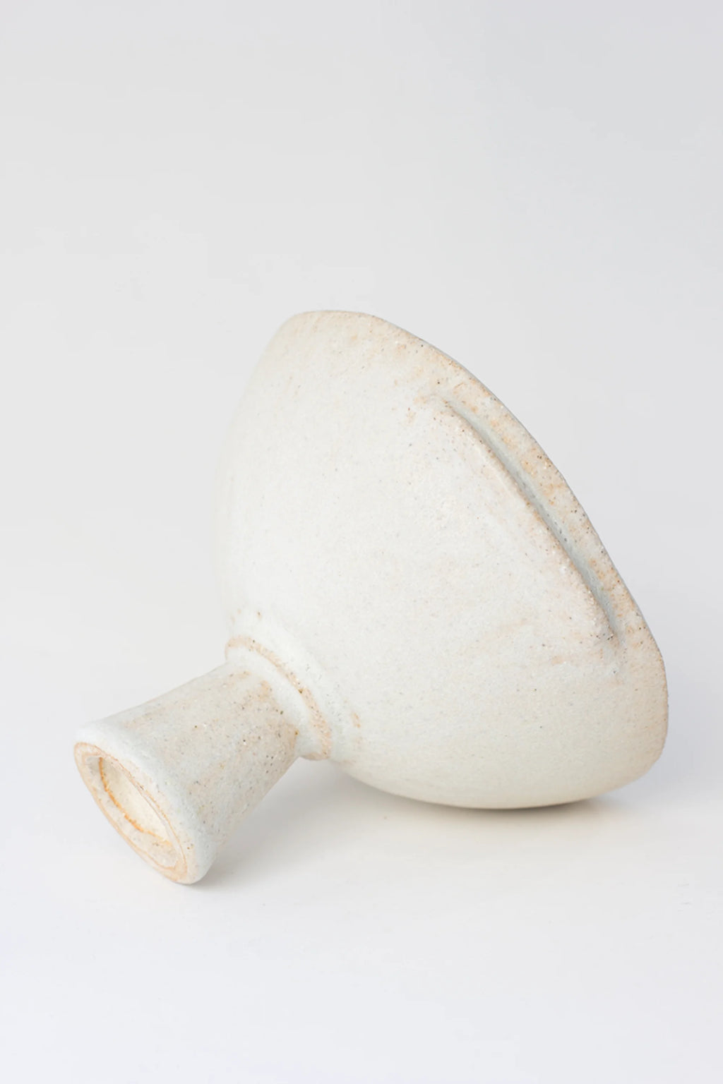 Canoa Lab Skypho Perla Footed Bowl, an artistic side view of the white ceramic bowl, showcasing its textured surface, unique handle-like protrusions, and sturdy footed design.