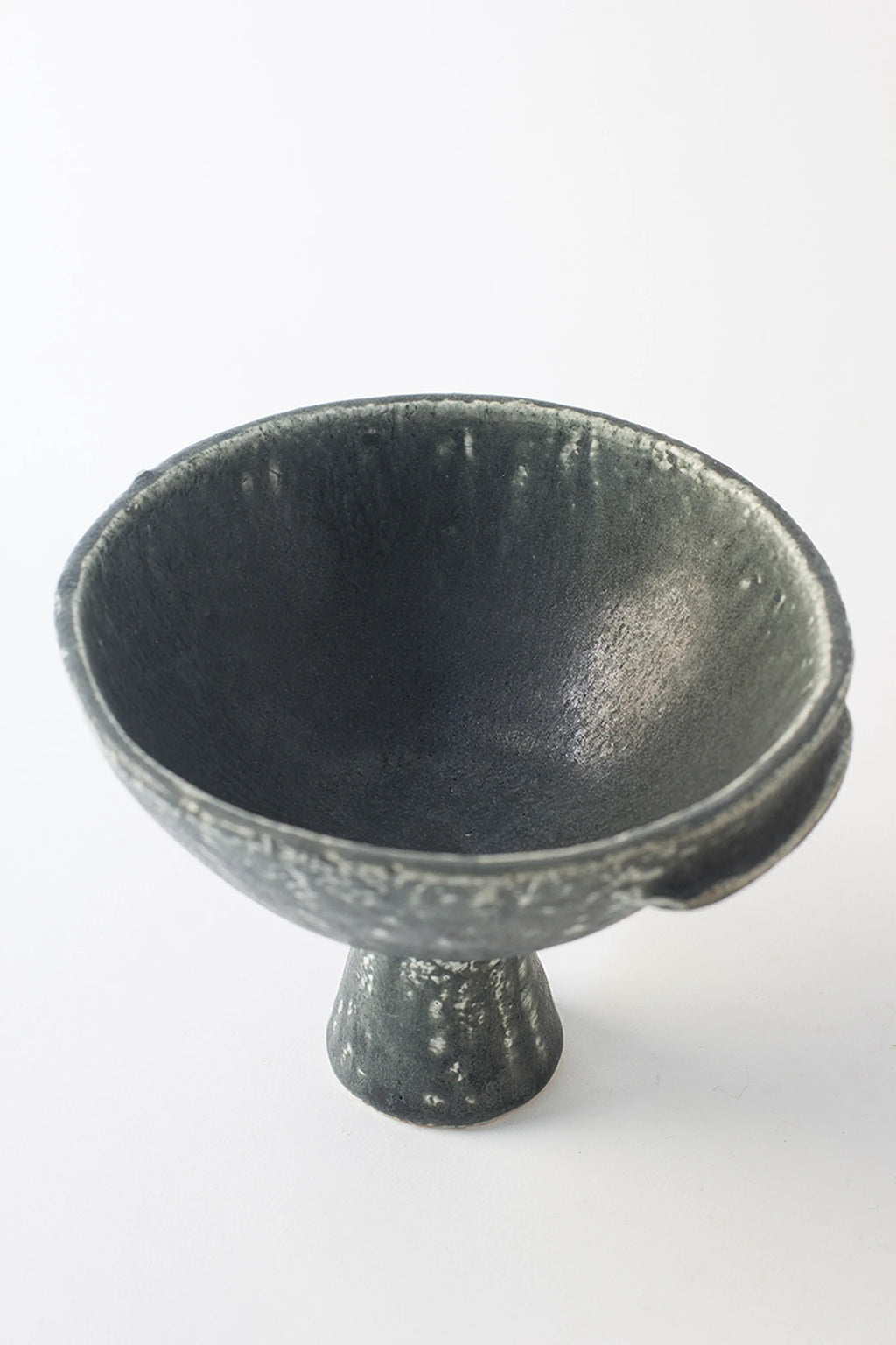 Canoa Lab Skypho Perla Negra Footed Bowl, a top-down angled view highlighting the deep interior and textured dark gray ceramic. The artisanal speckled finish and elegant footed design create a premium, modern aesthetic, displayed on a white background.