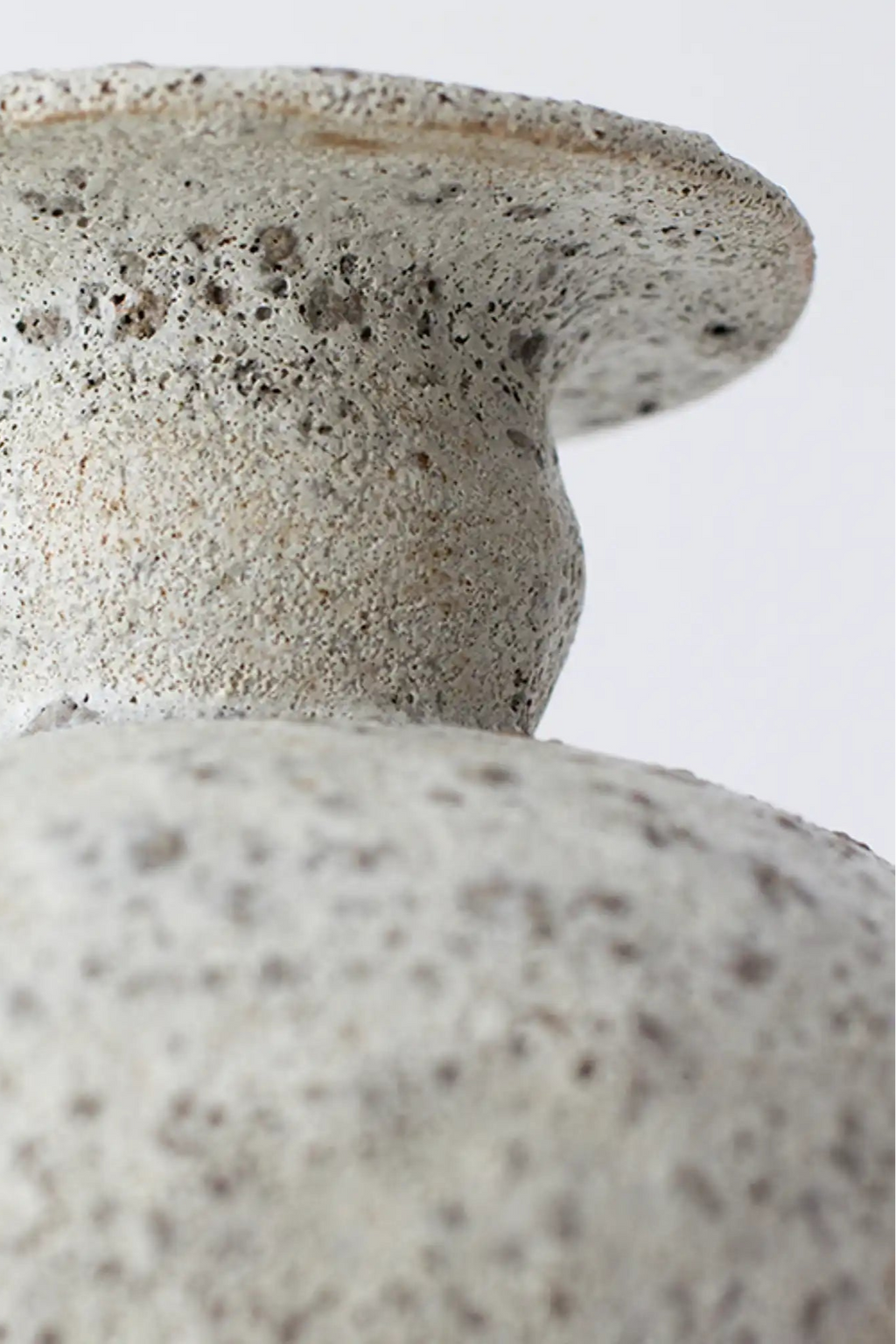 Canoa Lab Cálpide Vase, a handcrafted ceramic vase in a warm cream-colored tone, featuring a distinct porous volcanic texture with subtle dark speckles and a wide, flat rim.