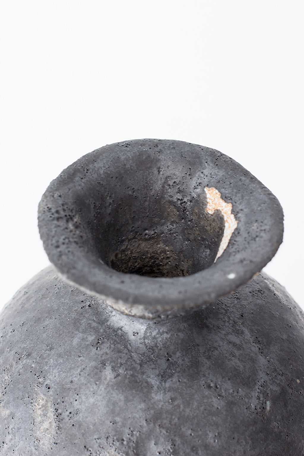 Canoa Lab Lekytho Vase, a dark grey handcrafted ceramic vase with a highly textured, porous volcanic finish and a unique organic shape, featuring a wide flared rim and subtle hints of natural terracotta. This artisanal stoneware piece is perfect for rustic, organic modern, or wabi-sabi home decor and shelf styling.