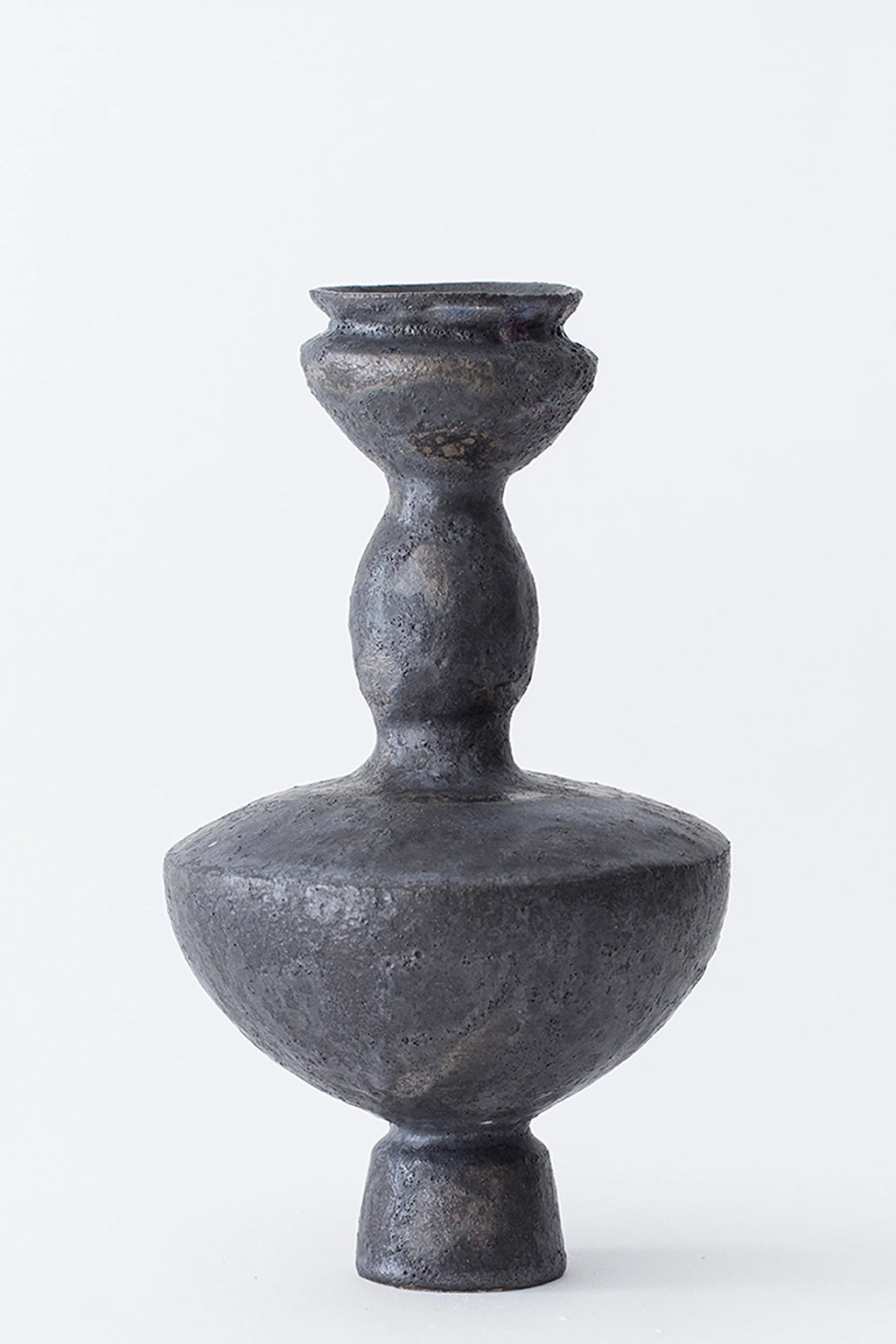 Canoa Lab Lutróforo Vase, a striking, dark charcoal gray ceramic vase with a textured, matte finish, featuring a classic, elegant silhouette with a wide base and a slender, tiered neck, on a white background.