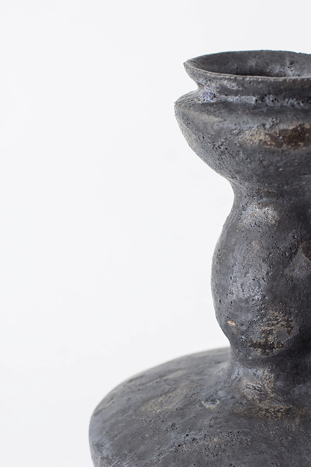 Canoa Lab Lutróforo Vase, a close-up side view of the dark gray ceramic vase, highlighting its rough, organic texture and the elegant curve of its neck, on a white background.