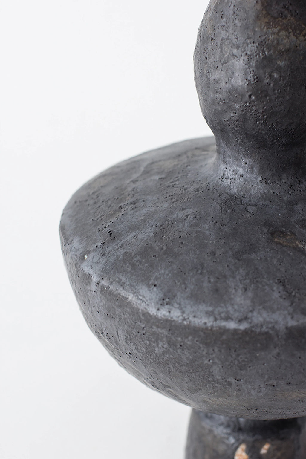 Canoa Lab Lutróforo Vase, an overhead close-up of the vase's shoulder, revealing the unique, porous texture and rich dark gray color of the artisanal ceramic, on a white background.