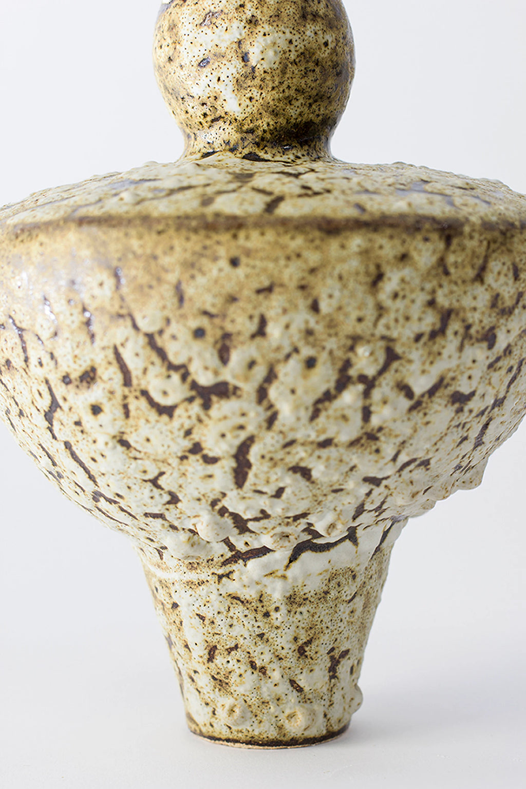 Canoa Lab Lydion Limonita Vase, a close-up of the lower body showcasing the intricate, organic texture and speckled brown-cream glaze, highlighting the artisanal craftsmanship on a white background.