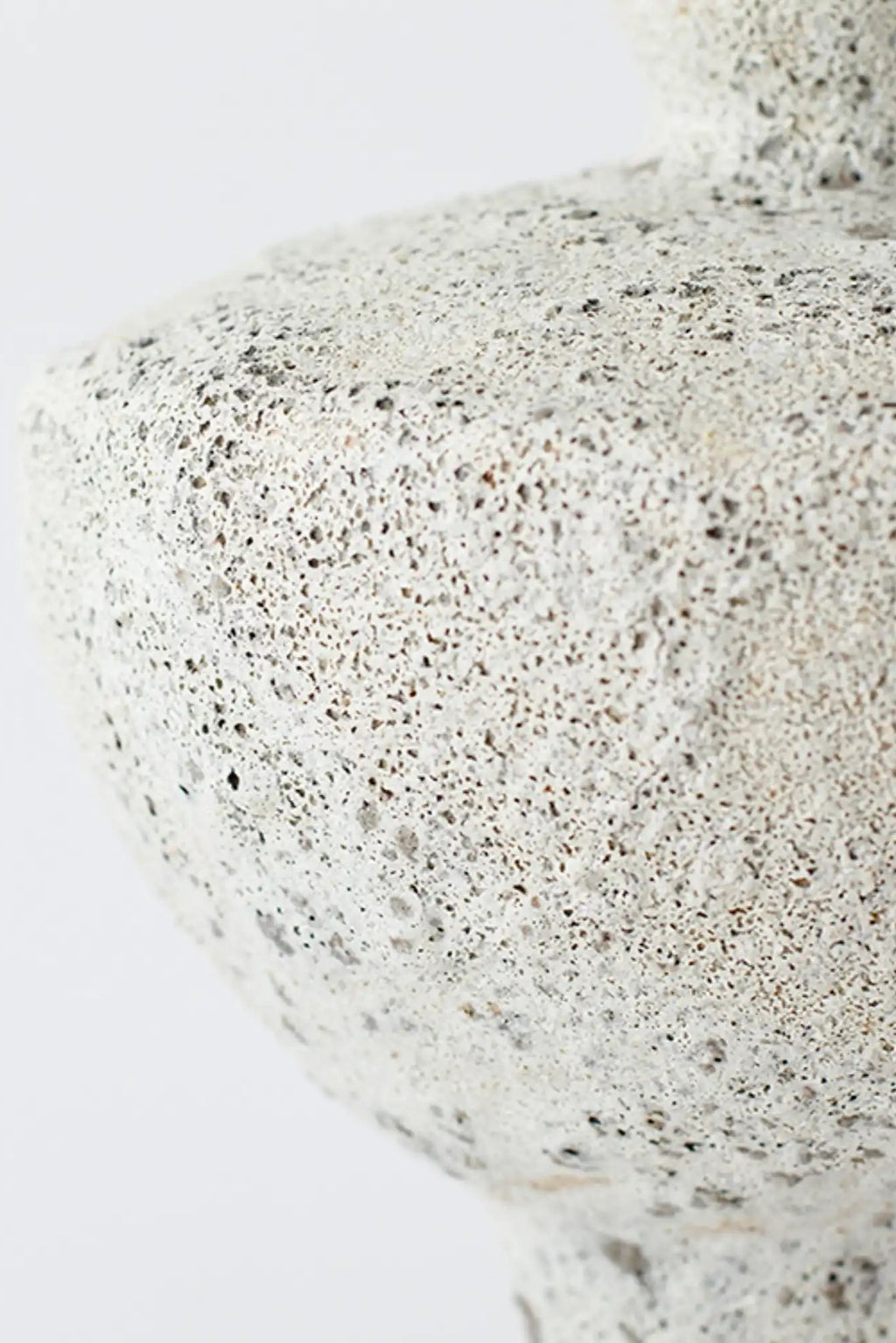 Canoa Lab Lydion Vase, a cream-colored handcrafted ceramic vase with a highly textured, porous volcanic finish, featuring dark grey and earthy speckles. This artisanal stoneware vase offers an organic modern aesthetic for minimalist shelf styling or japandi interiors.