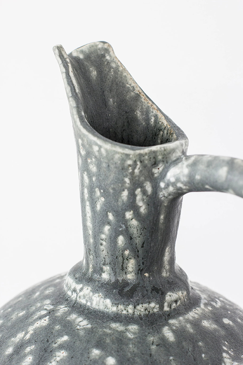 Canoa Lab Oinochoe Perla Negra Pitcher, a detailed view of the pitcher's spout and neck, emphasizing the unique speckled white glaze on the dark gray ceramic, revealing its handcrafted, rustic appeal.