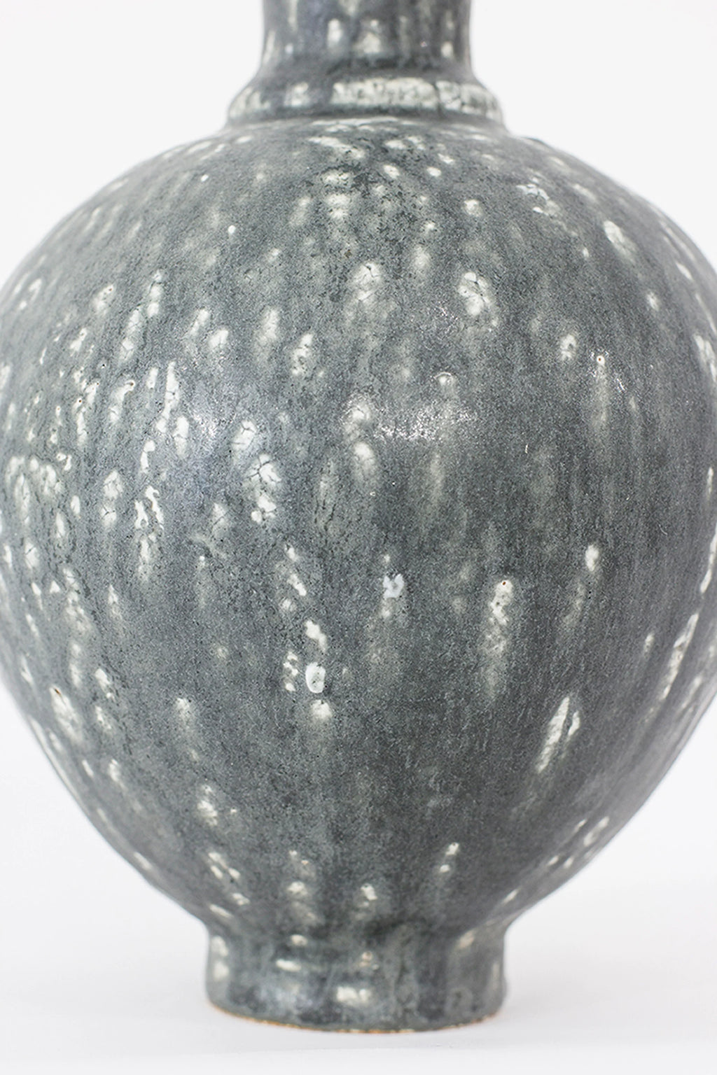 Canoa Lab Oinochoe Perla Negra Pitcher, a close-up of the pitcher's rounded body, highlighting the textured dark gray ceramic with distinctive speckled white glaze, showcasing its organic and modern aesthetic.