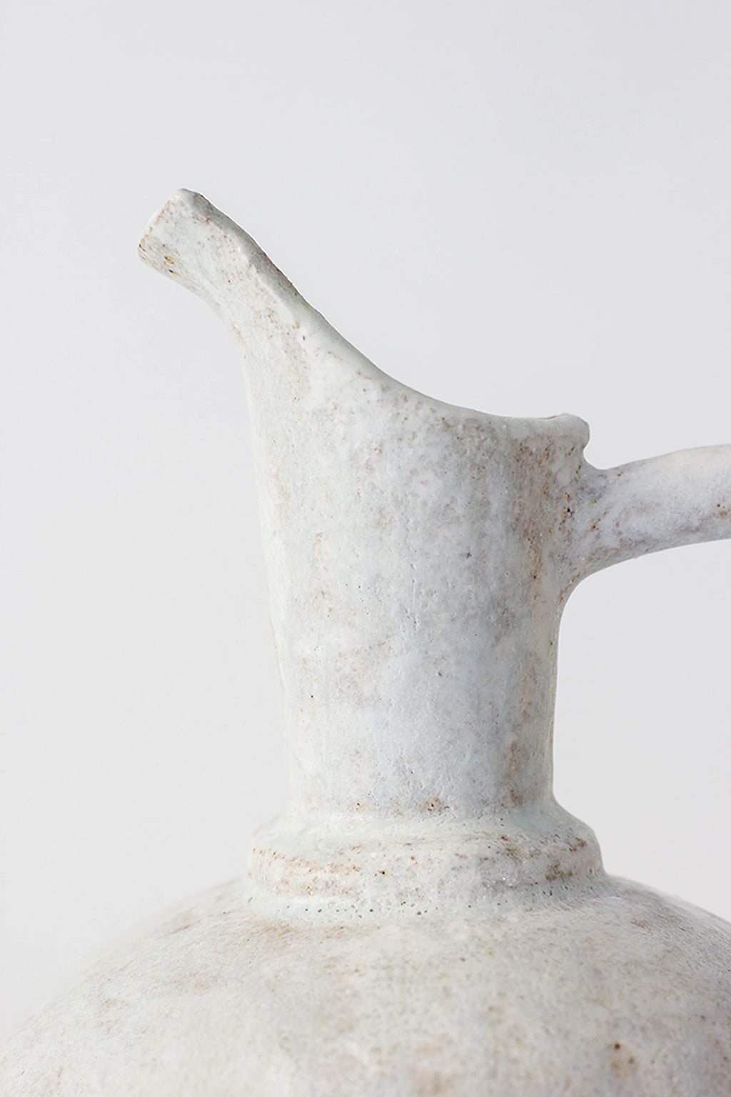 Canoa Lab Oinochoe Perla Pitcher, a handcrafted off-white ceramic pitcher featuring a heavily textured, porous stoneware finish with subtle natural speckles, an organic silhouette, and.