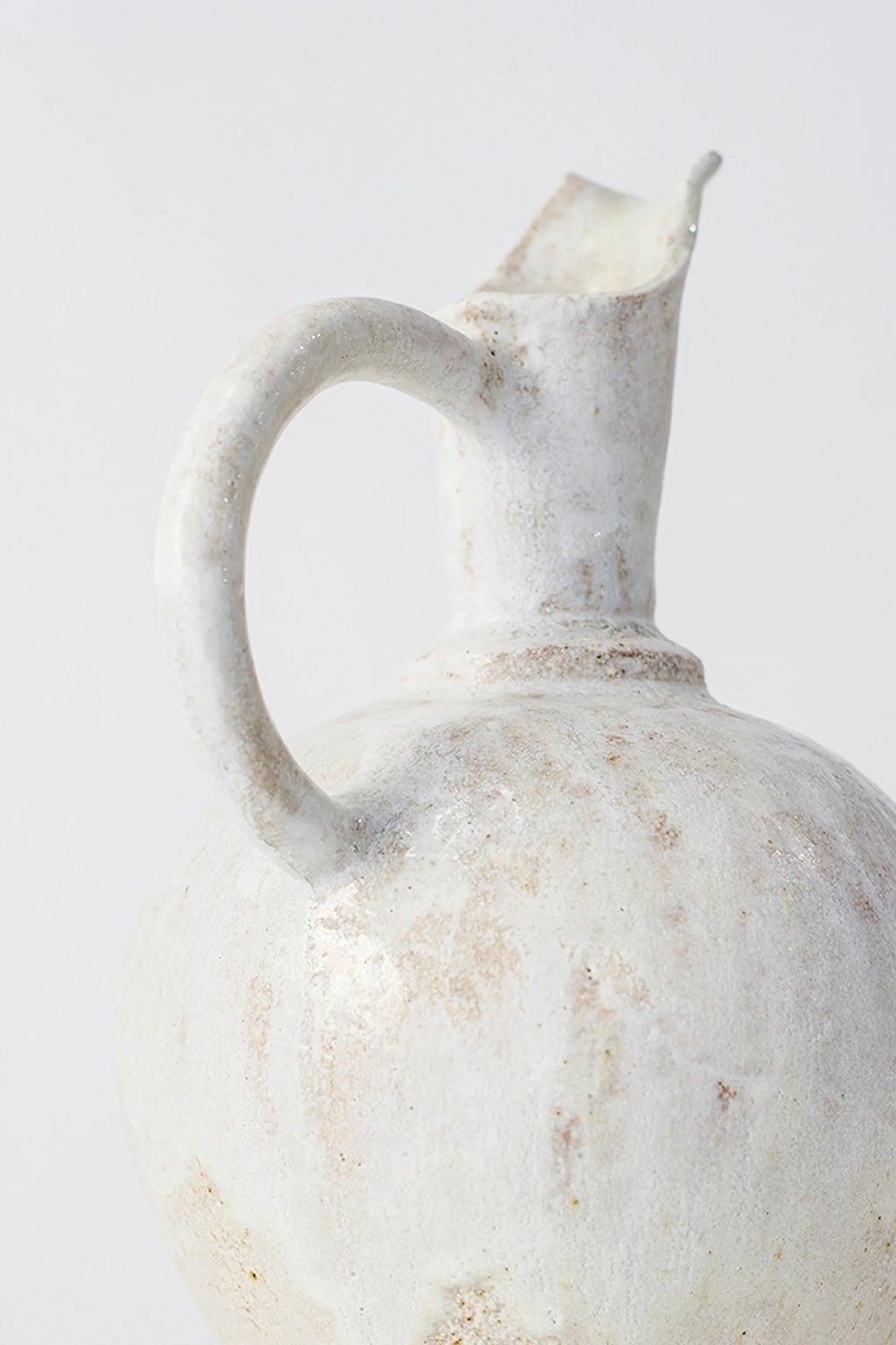 Canoa Lab Oinochoe Perla Pitcher, showcasing the full handle and upper body of the artisanal ceramic pitcher, with its textured off-white finish and delicate brown speckles, presented on a bright white background.