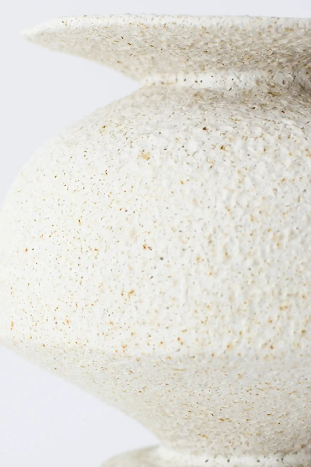 Canoa Lab Psychter Vase, a cream-colored handcrafted ceramic vase featuring a deeply textured, porous, and granular surface, reminiscent of natural sand or volcanic stone. This artisanal stoneware piece showcases a gently curved silhouette and a distinctive flared rim, embodying an organic modern aesthetic. Perfect for minimalist shelf styling or as a rustic accent in japandi and Mediterranean-inspired interiors.
