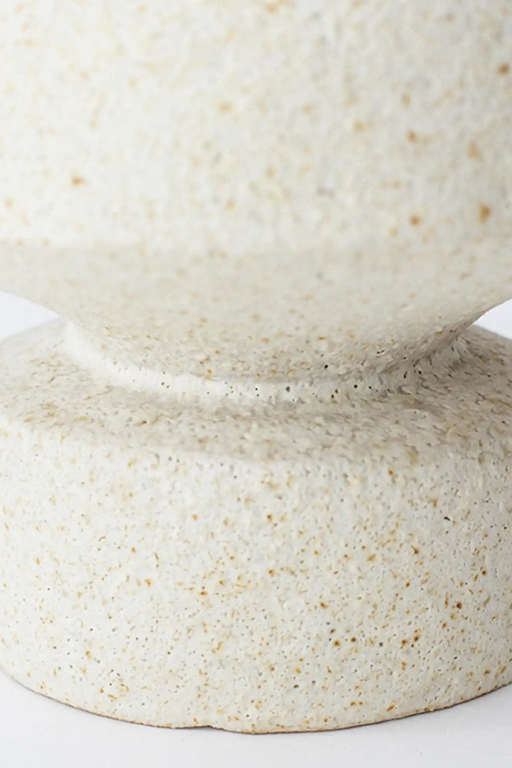 Canoa Lab Psychter Vase, a handcrafted stoneware vase in a warm cream and ivory speckled finish, featuring a distinctive porous, volcanic texture and a sculptural silhouette with a narrow, curved waist.