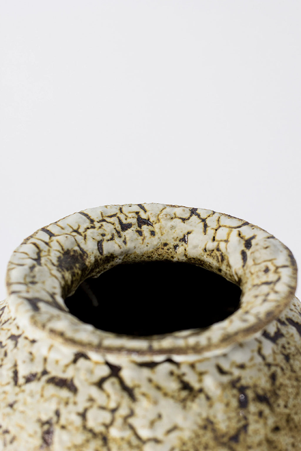 Canoa Lab Stamnos Limonita Vase, a close-up of the vase's unique ruffled rim and dark opening. The intricate crackled white and brown glaze texture is highlighted, emphasizing its artisanal and natural design on a white background.