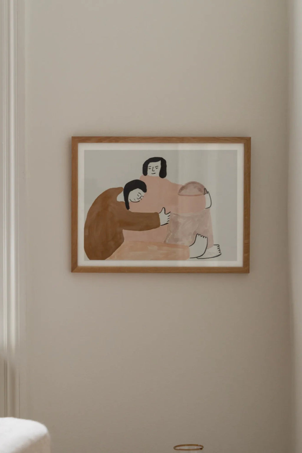 The Poster Club Stay Close, a minimalist abstract art print featuring two figures in muted pink and warm brown tones with simple black outlines on a light grey background, framed in a natural oak frame with a crisp white mat. This contemporary figurative wall art is ideal for modern living rooms, Scandinavian bedrooms, or as an accent piece in a gallery wall.