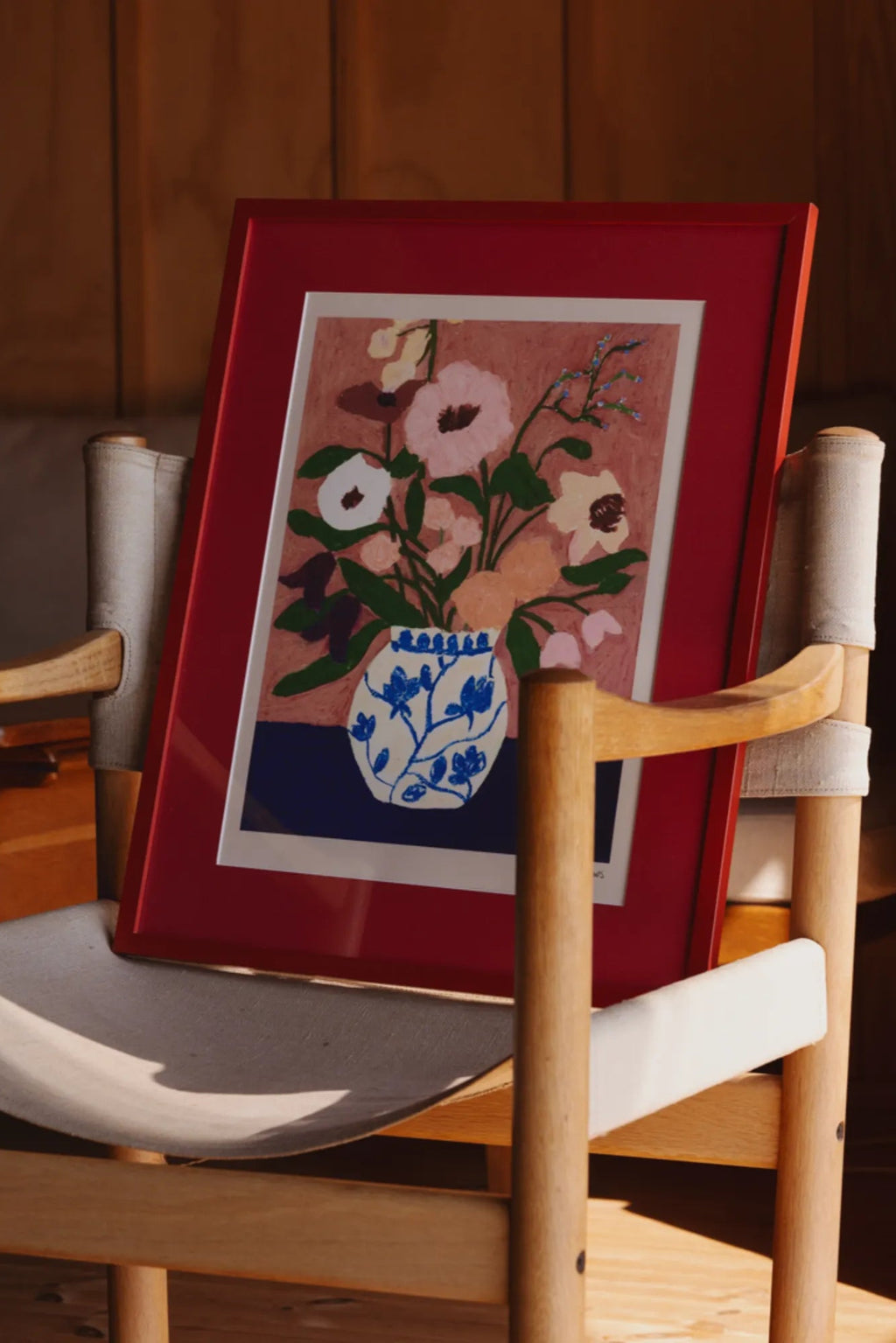 The Poster Club Flowers on Blue Table, a vibrant abstract floral art print featuring a bouquet of pink, peach, and cream flowers with green leaves in a blue and white patterned vase, set against a.